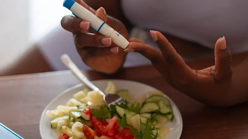 Person checking blood glucose with a meter before eating a salad