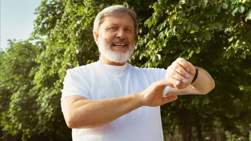 Older man checking his watch during a walk in the park